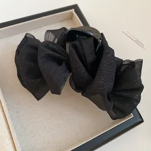 Detalle de pinza de pelo negra con volantes e hilos plateados para un peinado elegante y chic