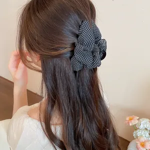 Vista detallada de una pinza para el cabello de lunares vintage en cabello castaño ondulado.