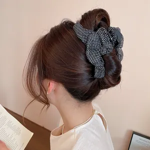 Primer plano de una pinza para el pelo con lunares blancos y negros estilo francés en un moño