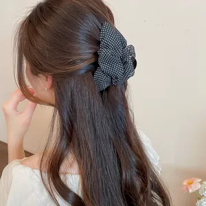 Vista detallada de una pinza para el cabello vintage con lunares blancos y negros en pelo largo