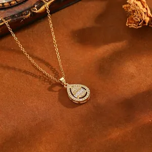 Detailed close-up of gold teardrop pendant with sparkling baguette and round pavé stones