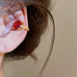 Λεπτομέρεια από επιχρυσωμένο σκουλαρίκι ear cuff με στρογγυλό κόκκινο ζιργκόν.