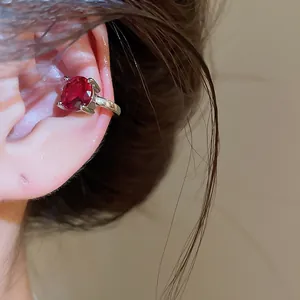 Κοντινό πλάνο κόκκινου ζιργκόν ear cuff που φοριέται στον χόνδρο του αυτιού χωρίς τρύπα