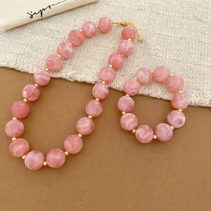 Close-up of pink acrylic round beaded necklace and bracelet set with gold spacers