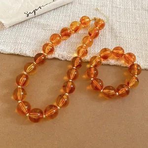 Macro view of amber acrylic round beaded necklace and bracelet jewelry set.