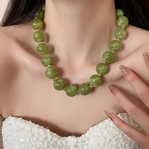Close-up detail of green marble-textured acrylic chunky bead necklace on model's neck