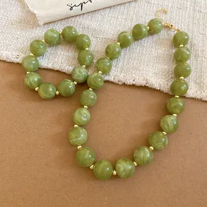 Detail view of green marbled acrylic round beaded necklace and bracelet jewelry set.