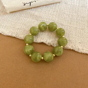 Detailed view of olive green acrylic beaded bracelet with marble pattern and gold spacers