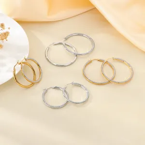 Vue détaillée de boucles d'oreilles créoles strass or et argent sur fond de soie beige élégant