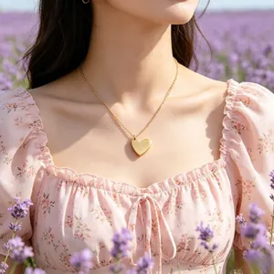 Close-up of a gold heart pendant necklace on a floral dress in a lavender field