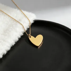 Macro view of gold heart pendant necklace on minimalist black and white background.