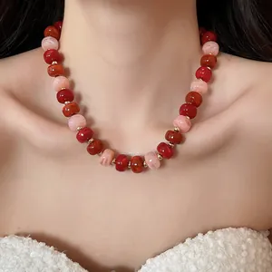 Vue rapprochée d'un collier en perles acryliques style Maillard aux tons rouges et roses