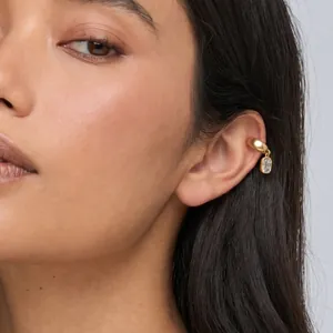 Close-up of gold stainless steel ear cuff with rectangular zircon pendant on model.