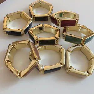 Dettaglio di vari braccialetti elastici in resina rettangolare con montature dorate lucide