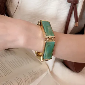 Dettaglio di bracciale elastico in resina marmorizzata verde con finitura dorata