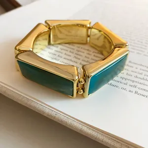 Vista dettagliata dei segmenti rettangolari in resina verde su bracciale elastico dorato