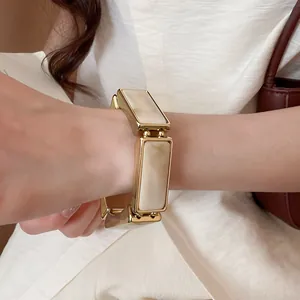 Dettaglio di un bracciale dorato in resina con venature color crema marmorizzate