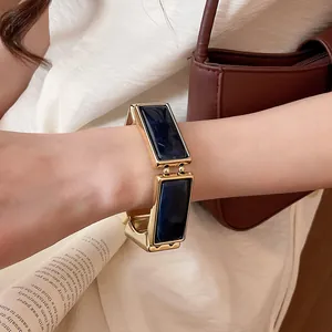Dettaglio di un bracciale rettangolare in resina con cornice dorata sul polso