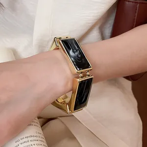 Dettaglio di un bracciale dorato vintage con segmenti rettangolari in resina marmorea.