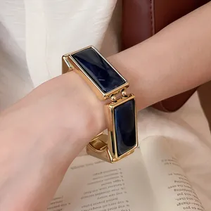 Primo piano di un bracciale rettangolare dorato con inserti in resina blu al polso