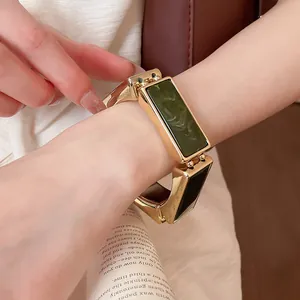 Primo piano di un bracciale retrò dorato con inserti in resina verde sul polso
