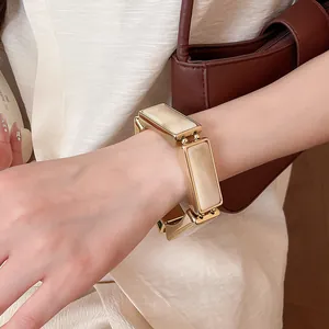 Primo piano di un bracciale elastico a giunture rettangolari in resina dorata sul polso