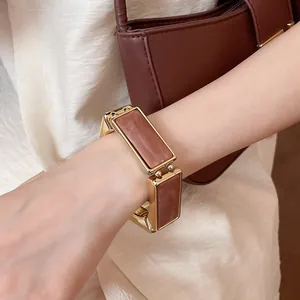 Dettaglio di un elegante bracciale elastico dorato con inserti rettangolari in resina malva