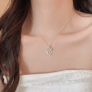 Elegant silver-tone necklace with zircon flower and white enamel bow pendant on model