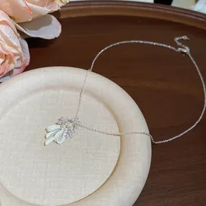 Elegant close-up of zircon flower and mint green enamel bow pendant on a silver necklace chain