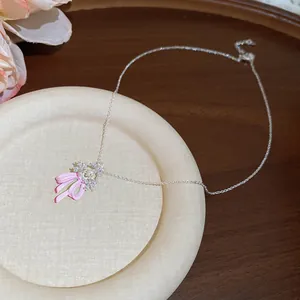 Close-up of pink enamel bow necklace with sparkling zircon flower pendant for women.