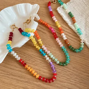 Macro shot of three colorful rainbow acrylic beaded necklaces with gold clasps on wood.
