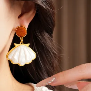 Eleganti orecchini a goccia a forma di conchiglia con perno in resina su modella per vacanze.