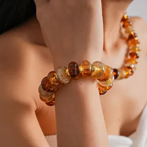 Close-up of amber marbled acrylic beaded bracelet and necklace set on model