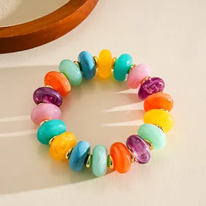 Close-up of a colorful marbleized acrylic bead bracelet with golden spacers.