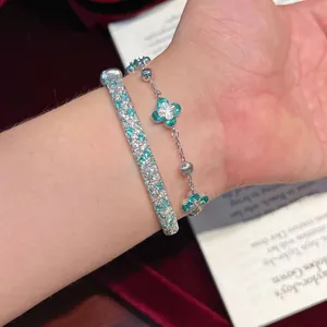 Primer plano de un elegante conjunto de pulsera floral verde menta y brazalete de plata en la muñeca.