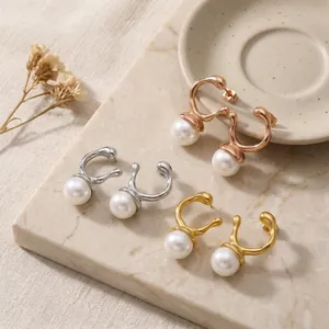 Macro shot of irregular C-shaped stainless steel earrings with elegant white pearls.