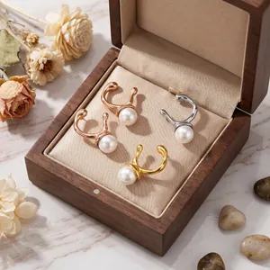 Detailed macro view of irregular geometric metal pearl earrings displayed in a wooden box