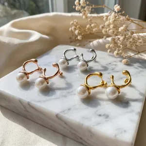 Close-up of irregular metal stud earrings with pearls in gold, silver, and rose gold