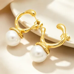 Close-up view of irregular gold-plated stainless steel earrings featuring large white pearls