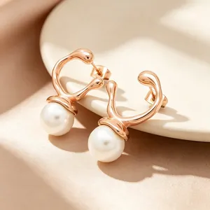 Close-up detail of rose gold irregular geometric earrings with elegant pearl drops
