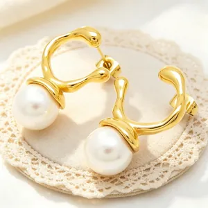 Close-up detail of gold irregular geometric stud earrings with large white pearls