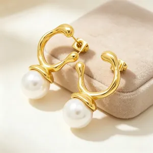 Close-up of irregular geometric gold earrings with large white pearls on a velvet box.
