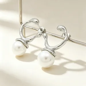 Macro detail of irregular geometric silver earrings featuring elegant white pearls.