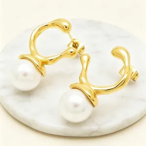 Detail view of irregular gold-plated stainless steel earrings with elegant white pearls