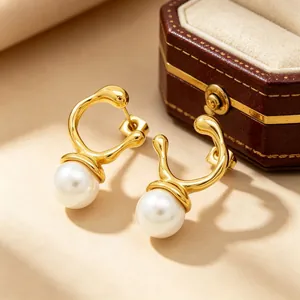 Detailed macro view of irregular gold stainless steel stud earrings with white pearls.