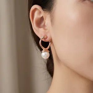 Detail of minimalist rose gold stainless steel earring with a single elegant white pearl