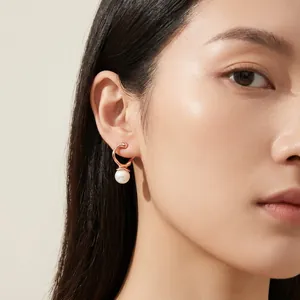 Detail shot of elegant rose gold stainless steel earrings with pearl drop on model