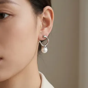 Close-up of minimalist irregular metallic earrings with a pearl drop on an Asian model