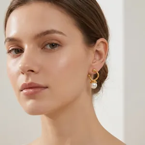 Close-up of minimalist irregular gold earrings with pearl on a female model
