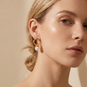 Detailed view of elegant gold irregular geometric pearl earrings worn by a model